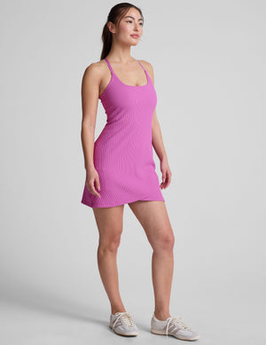 pink ribbed mini length dress with a soft scoop front neckline​, back strap cross-over detail, overlapping front hem detail​, and interior shorts ​with pockets. 