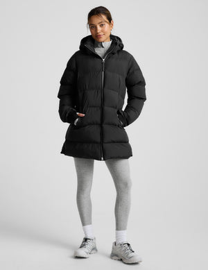 Person wearing a black puffer coat on a light gray background. 