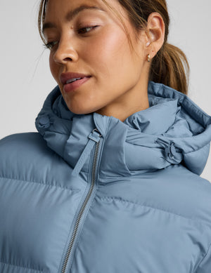 Woman wearing a blue puffer coat on a light gray background