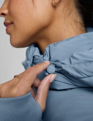 Woman wearing a blue puffer coat on a light gray background