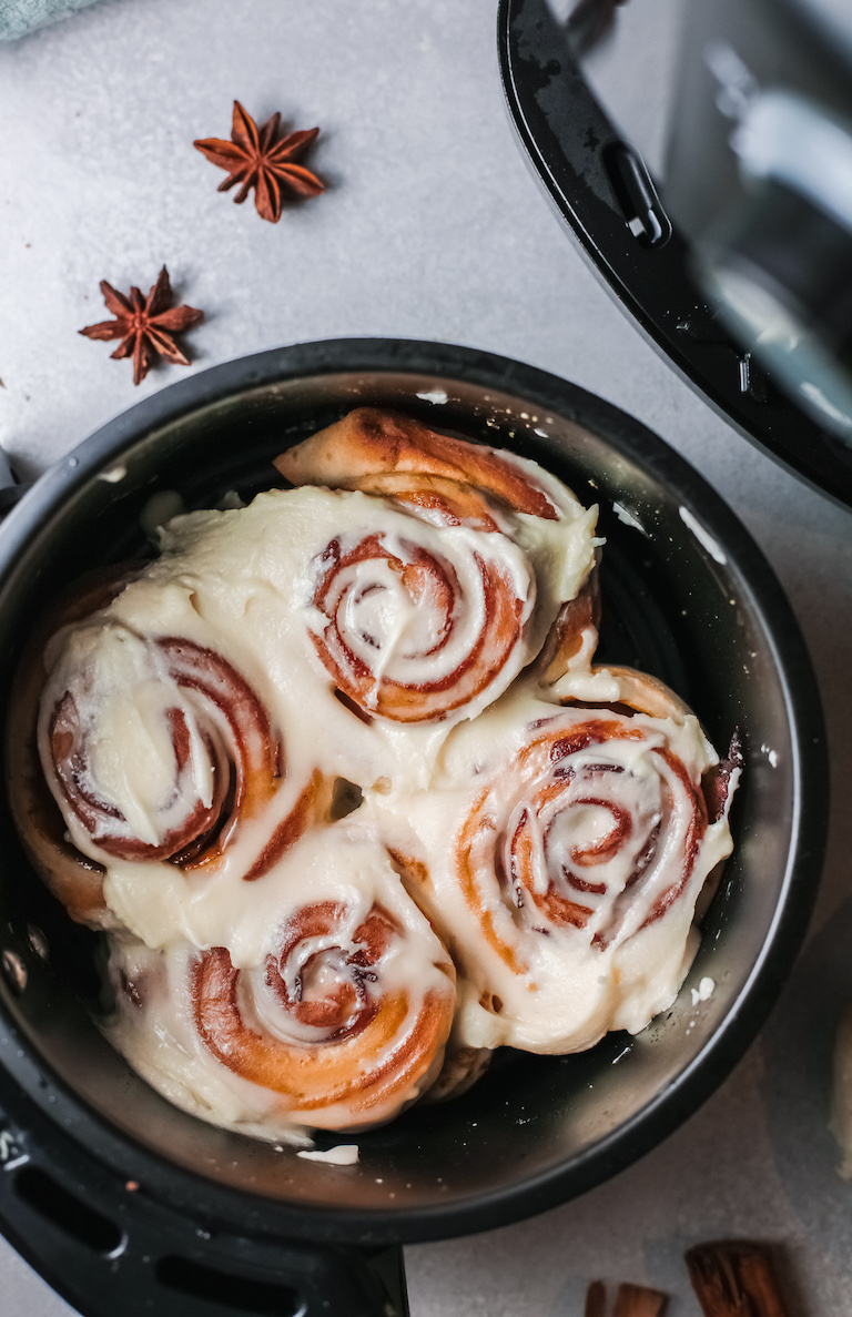 4 of the completed air fryer cinnamon rolls with bacon topped with frosting