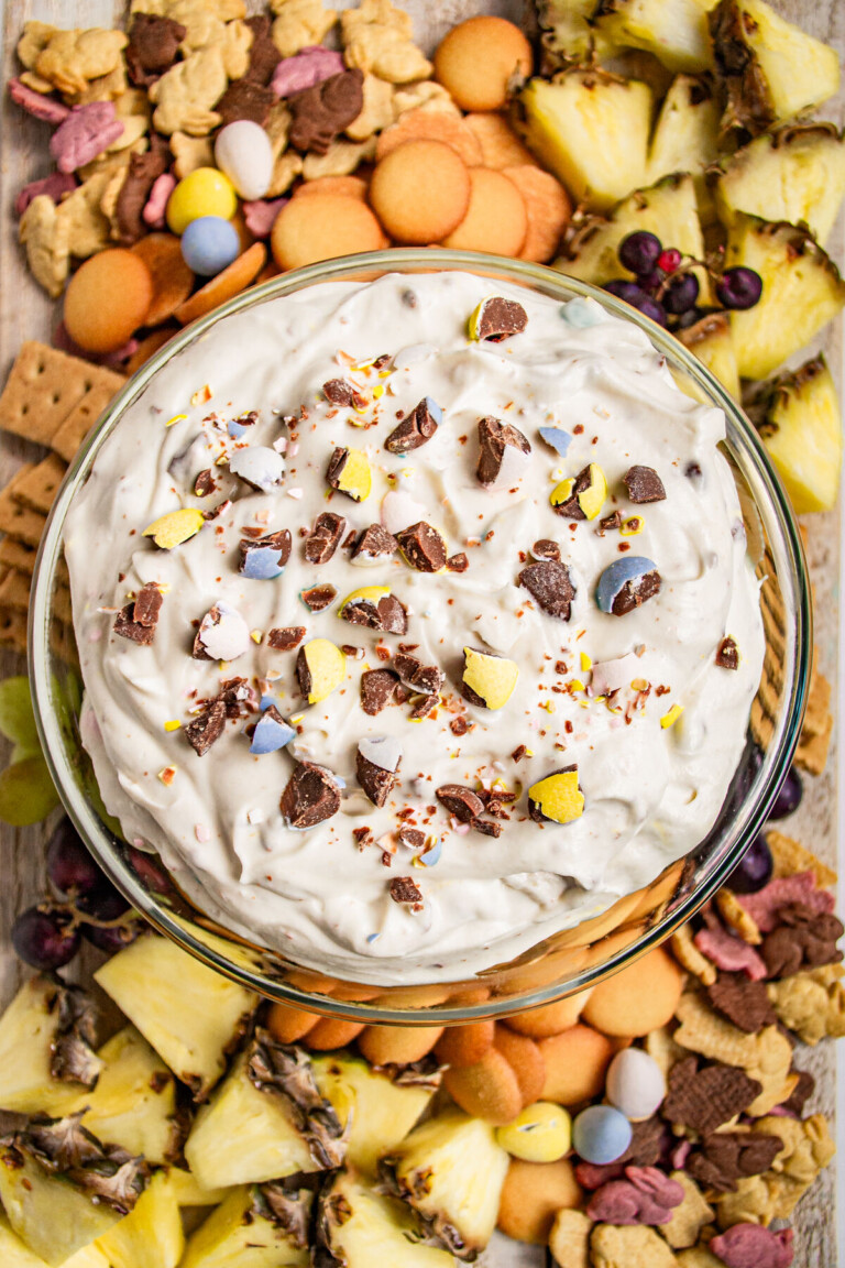 Overhead view of a dip with dippers from biscuits to fruit.