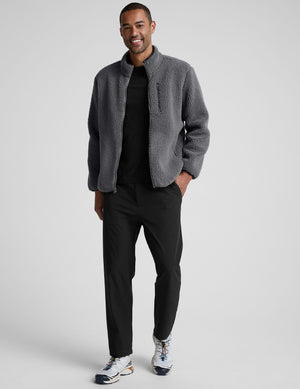 man wearing a gray fleece zip-up jacket against a plain background. 