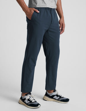 Person wearing navy pants on a plain background. 