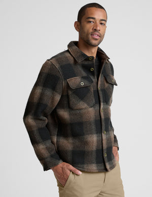 model wearing a men's plaid button-up jacket over a black shirt on a light gray background. 