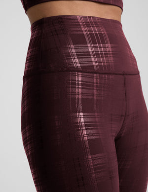 model wearing a plaid foil high-waisted midi leggings on a light gray background. 