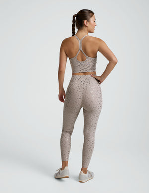 woman wearing high-waisted midi length beige leggings with a mini moon print against a plain background. 