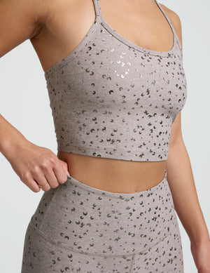 woman wearing high-waisted midi length beige leggings with a mini moon print against a plain background. 