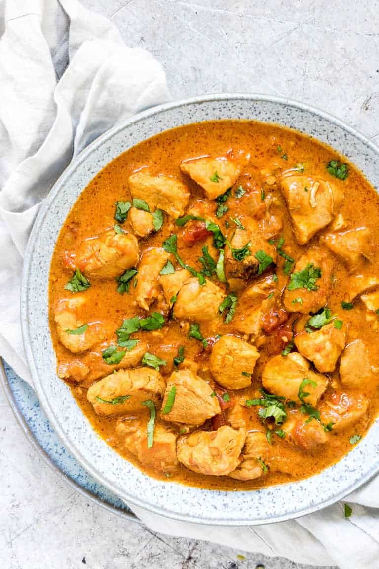 overhead view of instant pot chicken curry in a white bowl with towel underneath