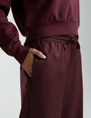 woman wearing a red sweatshirt and red faux leather wide leg pants against a plain background. 