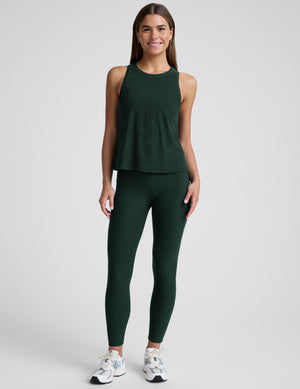 model wearing a green relaxed fit tank top and leggings against a plain background. 