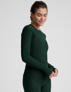 model wearing a green fitted crew neck long-sleeve top against a light gray background. 