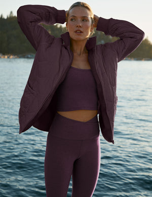 Woman in purple athletic wear standing by a body of water. 