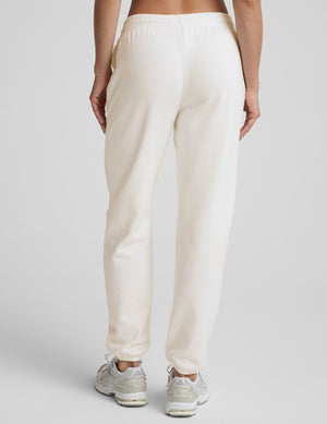 woman wearing white fleece sweatpants against a plain background. 