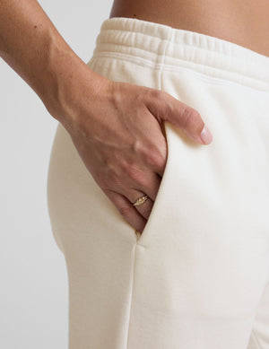 woman wearing white fleece sweatpants against a plain background. 