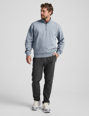 Man wearing a light blue half-zip sweatshirt against a plain background.