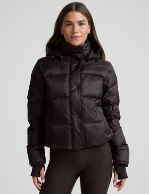 woman wearing a brown puffer jacket on a plain background. 