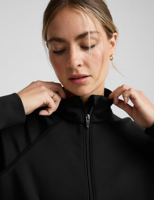 Woman wearing a black tracksuit on a light gray background. 