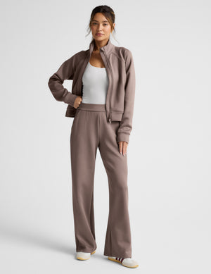 Woman wearing a brown tracksuit on a light gray background. 