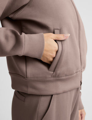 Woman wearing a brown tracksuit on a light gray background. 