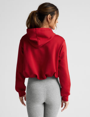 Woman wearing a red hoodie and gray leggings on a white background. 