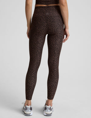 person wearing brown leopard print leggings on a plain background. 