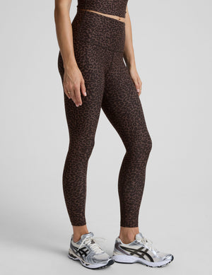 person wearing brown leopard print leggings on a plain background. 