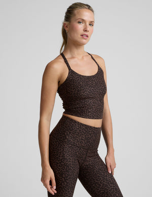 woman wearing a brown leopard print cropped tank and leggings on a gray background. 
