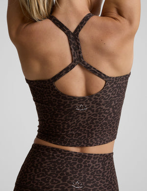 woman wearing a brown leopard print cropped tank and leggings on a gray background. 