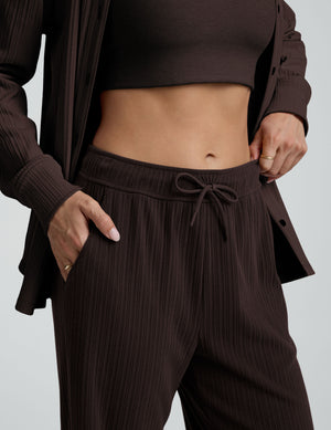 model wearing brown ribbed wide leg pants with a drawcord at waistband against a plain background. 