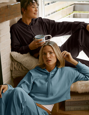 Two people sitting on a couch wearing matching blue and brown hoodies.