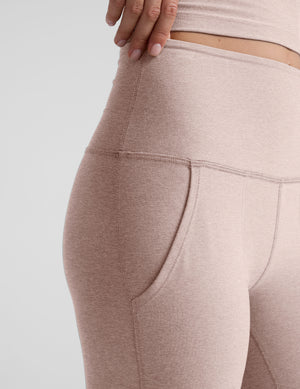 model wearing pink high-waisted bootcut pants with pockets set on a plain background.