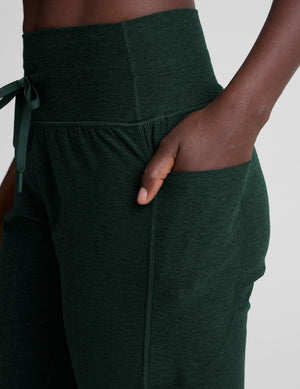 model wearing green midi length joggers with a drawcord at the waistband against a plain background. 