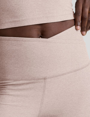 model wearing pink high-waisted leggings with a front crossover detail on a plain background. 