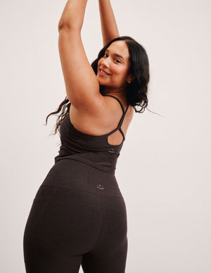 woman wearing a brown racerback cropped tank on a plain background. 