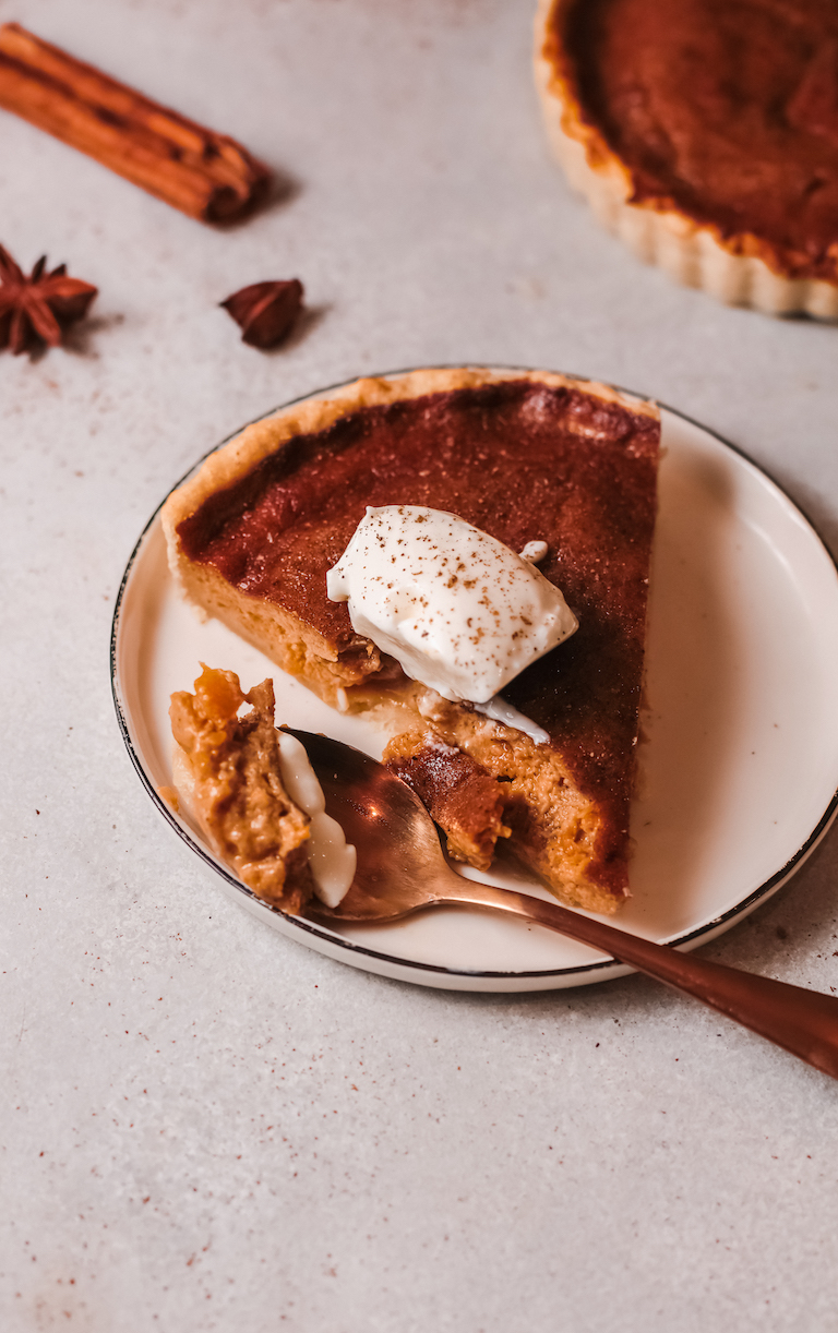 a slice of sweet potato pie served on a dessert plate with a bite removed