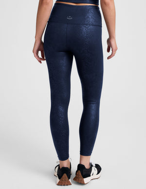 Woman wearing a navy viper printed leggings blue on a plain background. 