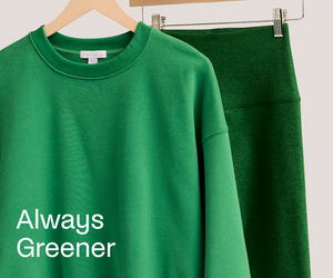Green sweatshirt with 'Always Greener' text on a hanger against a white background